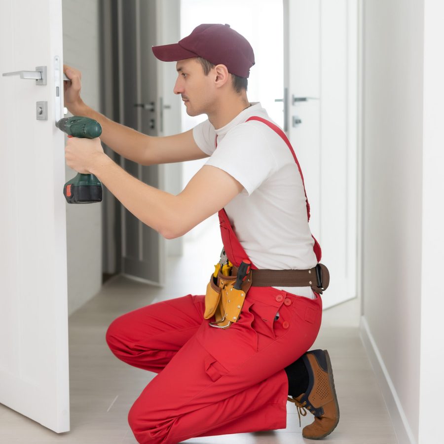 The master worker installs a door lock in the front door, metal doors with a polymer coating.